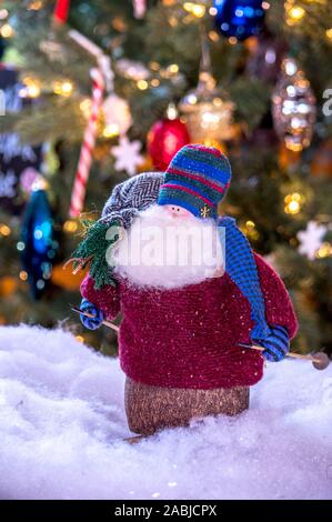 Un vecchio barbuto Santa doll sci in Natale con un sacco sulle spalle dei giocattoli di contenimento ad un piccolo albero Foto Stock