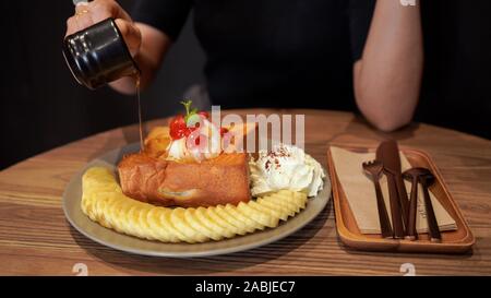 Versa manualmente il miele sul pane tostato e gelato, miele Toast. Foto Stock