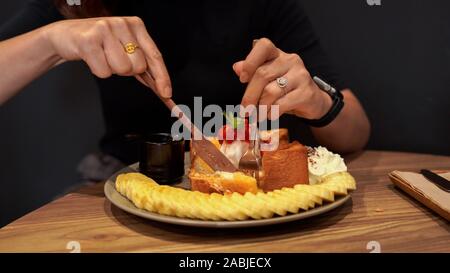 Mani Forchette e coltelli di taglio su un miele toast Foto Stock