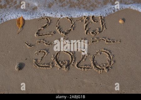 La Vigilia di Capodanno 2019, accoglie 2020 Scritta sulla sabbia mentre l'acqua di una forma d'onda è venuta a cancellare il script 2019 Foto Stock