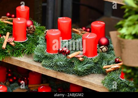 Tradizionale ghirlande con quattro candele rosse e stagionali per le decorazioni di Natale per la vendita sul ripiano di legno Foto Stock