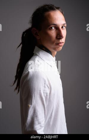 Giovane imprenditore con dreadlocks contro uno sfondo grigio Foto Stock