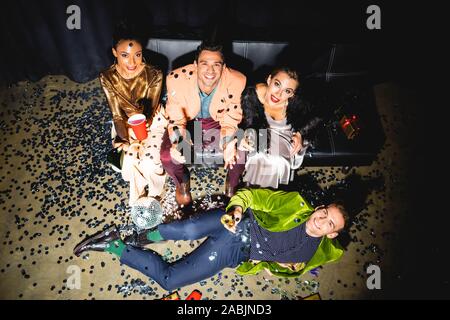Vista aerea di allegro multiculturale di uomo e donna che mantiene le bevande vicino a palla da discoteca Foto Stock