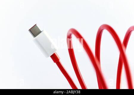 Close-up di rosso arrotolato tipo USB-C del cavo su sfondo bianco Foto Stock