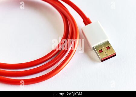 Close-up di red arricciata cavo USB su sfondo bianco con spazio di copia Foto Stock