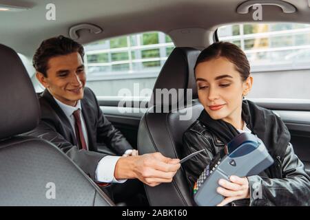 Imprenditore pagando con carta di credito in taxi Foto Stock