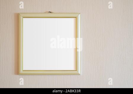 Un vero e proprio moderno cornice fotografica con ornamenti d'oro e la copia in bianco di spazio, per l'inserimento di qualsiasi immagine, su una parete ricoperta con dipinto di beige sfondo. Foto Stock