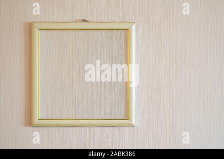 Un vero e proprio moderno cornice fotografica con ornamenti d'oro e la copia in bianco di spazio, per l'inserimento di qualsiasi immagine, su una parete ricoperta con dipinto di beige sfondo. Foto Stock