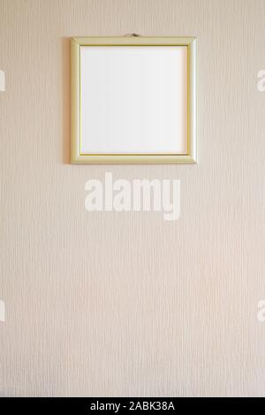 Un vero e proprio moderno cornice fotografica con ornamenti d'oro e la copia in bianco di spazio, per l'inserimento di qualsiasi immagine, su una parete ricoperta con dipinto di beige sfondo. Foto Stock