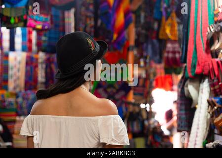 Osservando turistiche artigianato guatemalteco nel mercato circondata da colori tradizionali in Antigua Guatemala Foto Stock