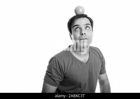 Studio shot del giovane uomo persiano pensare guardando apple sulla cima della sua testa isolata contro uno sfondo bianco Foto Stock