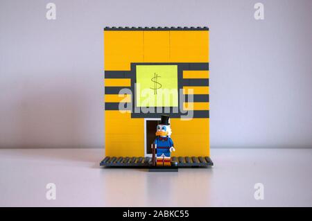 Una improvvisata struttura lego di Uncle Scrooge il denaro bin. Uncle Scrooge figurina in piedi nella parte anteriore del vassoio. Foto Stock