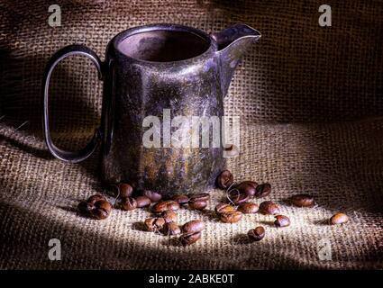 Tavolo rustico ricoperto con tela con vintage tazza metallico e i chicchi di caffè su di esso close up Foto Stock