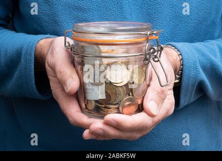 L'uomo mani tenendo il vaso pieno di euro denaro, il concetto di fondo pensione, monete e banconote in euro Foto Stock