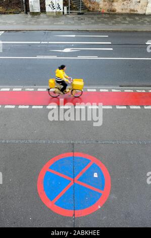 Un postino sulla sua bicicletta rigidi passato un grande no-simbolo di parcheggio. [Traduzione automatizzata] Foto Stock