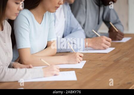 Close up razza mista agli studenti di scrivere test accademico. Foto Stock