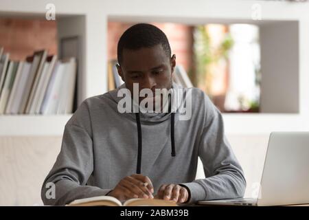 Concentrato maschio americano africano studente prepara per l'esame finale. Foto Stock