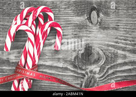 Candy canes avvolto con red Natale nastro su nero e sfondo bianco. Vista da sopra con copia spazio sul lato destro. Foto Stock