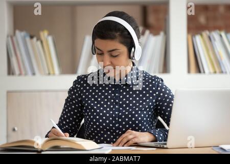 Indiano focalizzato studentessa la preparazione per gli esami, indossare la cuffia. Foto Stock