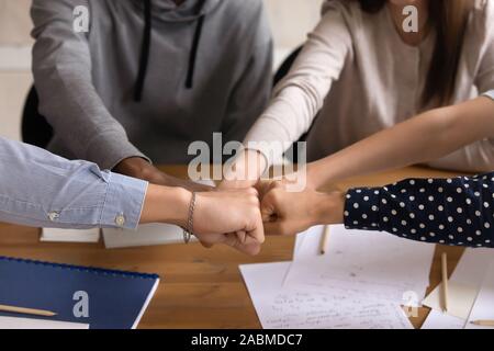 Close up vista laterale razza mista studenti motivati bumping pugni. Foto Stock