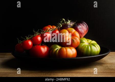 Pomodori diversi su una piastra nera Foto Stock