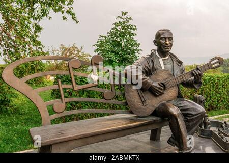 Krasnoyarsk, Russia, Agosto 25, 2019: bronzo uomo suonare la chitarra, bench panca per amanti e sposi novelli, street monumento, attrazioni, luoghi per turiste Foto Stock