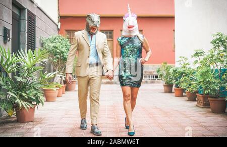 Crazy coppia senior indossando di dinosauro e maschera unicorno - coppia alla moda di persone aventi una divertente mascherata alla sfilata di carnevale Foto Stock