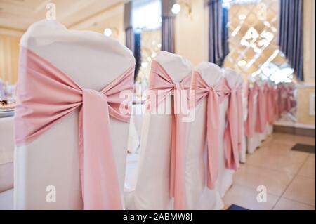 Bellissimo set di nozze decorazione nel ristorante. Rosa nastri su sedie. Foto Stock