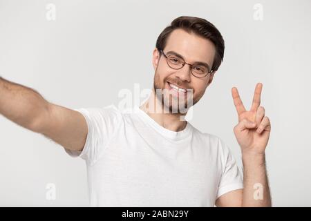 Sorridente uomo millenario in vetri rendono selfie in studio Foto Stock