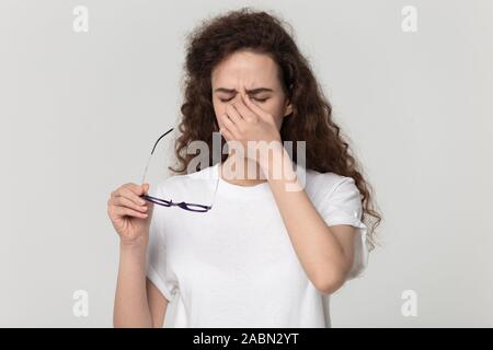 Stanco ragazza millenario togliere i bicchieri che soffrono di mal di testa Foto Stock