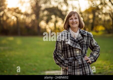 Ritratto di felice senior donna nel parco in autunno. Foto Stock