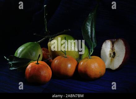 Limone e frutta tamiringe con una mezza mela su uno sfondo blu scuro Foto Stock