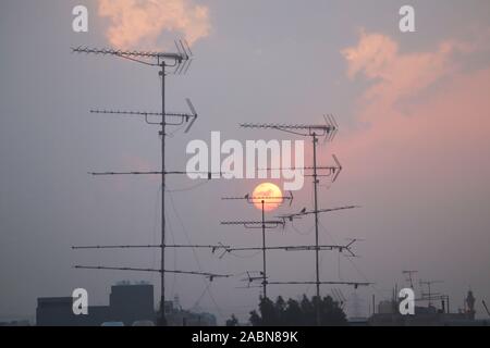 Antenna televisione stagliano contro una regolazione del sole Foto Stock