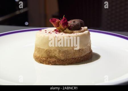 Senza zucchero dessert cocco sulla piastra bianca. Decorata con fiori e cioccolato senza zucchero. Cibo sano. Foto Stock