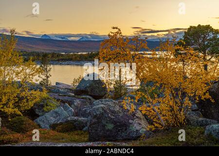 Vista su Stora Lule vatten con montatura Akka in background, al tramonto, bei colori nel cielo che riflette nell'acqua, e gli alberi sono di colore giallo in autunno mari Foto Stock