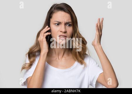 Infastiditi arrabbiato donna quarreling parlando al telefono, audizione cattive notizie Foto Stock