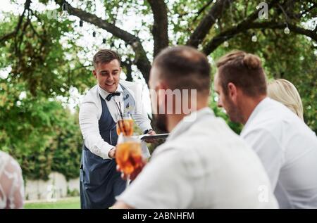 Felice volte. Gruppo di amici adulti hanno un resto e la conversazione nel cortile del ristorante a cena Foto Stock