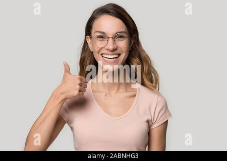 Emozionato felice giovane donna con gli occhiali che mostra pollice in alto Foto Stock