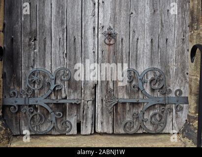 Ornati di cerniere di ferro e porta-respingente sul weathered argentato antica porta di legno della chiesa a Bradfield, Sheffield South Yorkshire, Inghilterra, Regno Unito Foto Stock