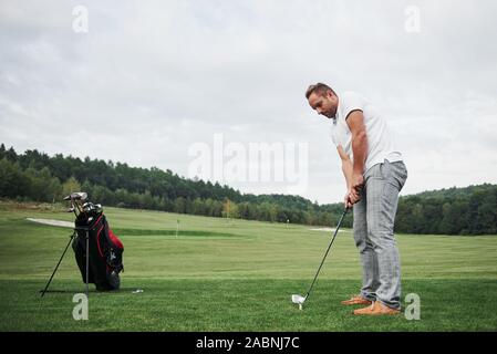In Pro Golf player volto girato con club in corso. Golfista maschio sul putting green per prendere il colpo Foto Stock