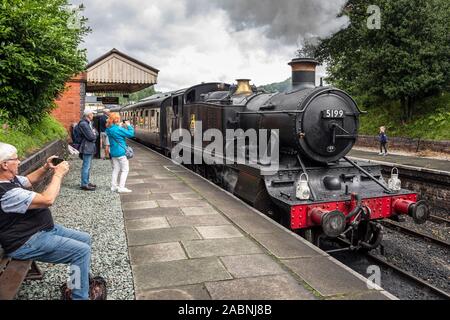 I turisti a guardare un motore a vapore lasciando la stazione di Llangollen, Llangollen Railway, Denbighshire, Galles Foto Stock