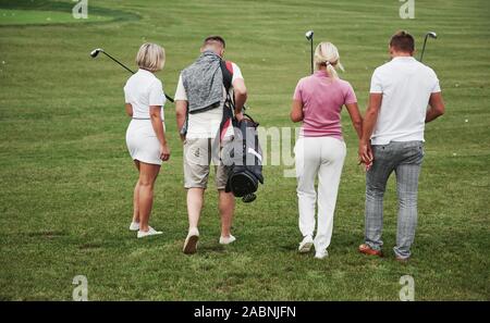 Il gruppo di amici di stile sul campo da golf impara a giocare una nuova partita. La squadra sta andando a riposo dopo la partita Foto Stock