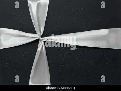 Nastro argentato legato attorno a dark glittery sfondo, il minimo regalo di Natale concept Foto Stock