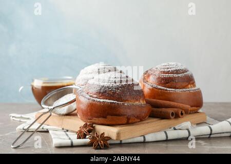 Gustosa cinnamon roll con ingredienti, caffè sul tavolo marrone contro sfondo blu, spazio per il testo. Vista superiore Foto Stock