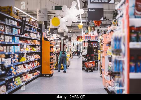 Strasburgo, Francia - Dic 21, 2016: interni di grandi francese supermercati Auchan con il lavoratore la preparazione di merci destinate ad essere disposte sugli scaffali e clienti shopping Foto Stock