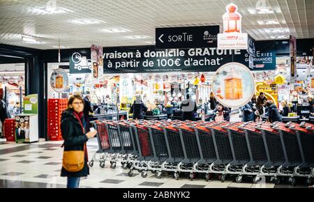 Strasburgo, Francia - Dic 21, 2016: silhouette di donna in attesa vicino i carrelli di shopping nella grande francese supermercato Auchan Foto Stock