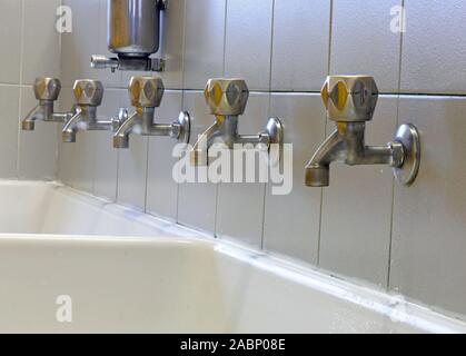 Lunga fila rubinetti della grande scuola lavabo senza figli e il Distributore sapone Foto Stock