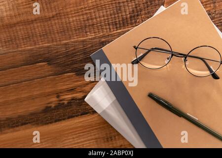 Notebook, quotidiani e occhiali su tavole di legno, tavoli di lavoro, display decorazioni, Foto Stock