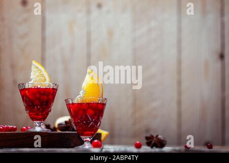 Vintage due bicchieri di vino brulé con mirtilli rossi, fettine di arancia e anice stellato su tavola in legno rustico, close up Foto Stock