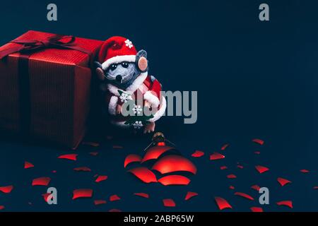 Sfondo di natale. Xmas ratto, topo giocattolo, simbolo cinese di felice anno nuovo 2020. Close up mouse giocattolo in santa claus Red Hat e Nuovo Anno decorazioni. hor Foto Stock